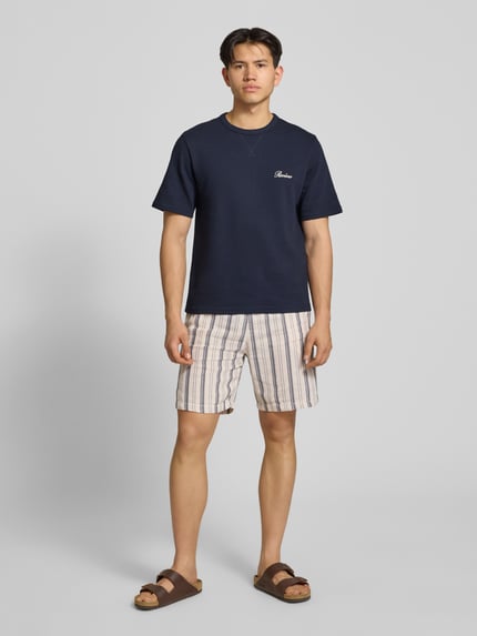 Männermodel trägt T-Shirt mit Label-Stitching von REVIEW aus Baumwoll-Mix in Dunkelblau, Struktur in Waffeloptik, gerader Schnitt, Ganzkörperansicht von vorne.