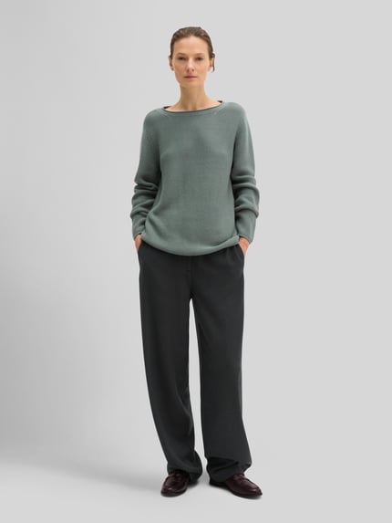 Frauenmodel trägt Regular Fit Pullover aus reiner Baumwolle von MARC O'POLO in Strickoptik, unifarben, langarm, U-Boot-Ausschnitt, Ganzkörperansicht von vorne.