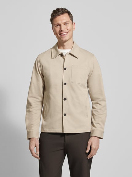 Männermodel trägt Relaxed Fit Hemdjacke mit Brusttasche von Lindbergh in Beige, Material-Mix, Umlegekragen, Knopfleiste, Ganzkörperansicht von vorne.