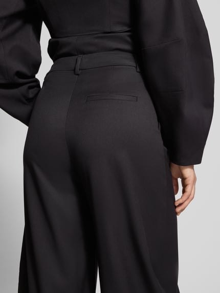 Frauenmodel trägt Barrel Fit Hose mit Viskose-Anteil Modell 'Callia' von Gestuz, schwarze Struktur, Bundfalten, Detailaufnahme Rückansicht.