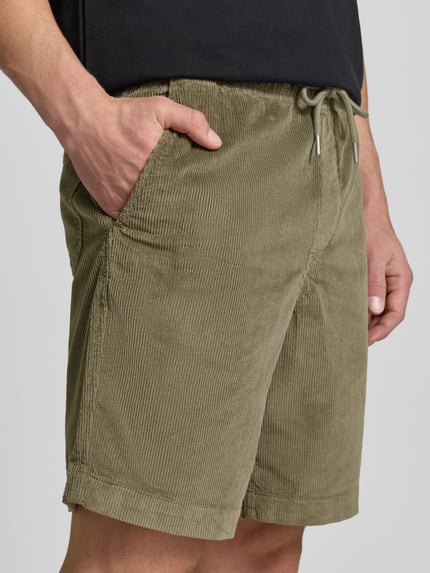 Mężczyzna nosi Regular Fit Sweatshorts aus Baumwoll-Mix von SELECTED HOMME, zielony sztruks, kieszenie boczne, gumka w pasie, widok z przodu, zbliżenie na górną część ciała.