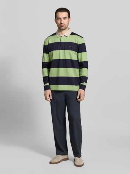 Männermodel trägt Regular Fit Poloshirt mit Streifenmuster und Label-Stitching von Fynch-Hatton, grün-blau gestreift, Baumwolle, Ganzkörperansicht von vorne.