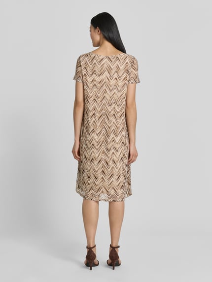 Frauenmodel trägt Regular Fit Freizeitkleid mit Lochstrickmuster von s.Oliver BLACK LABEL in Beige-Braun mit Zickzackmuster, Ganzkörperansicht Rückansicht.
