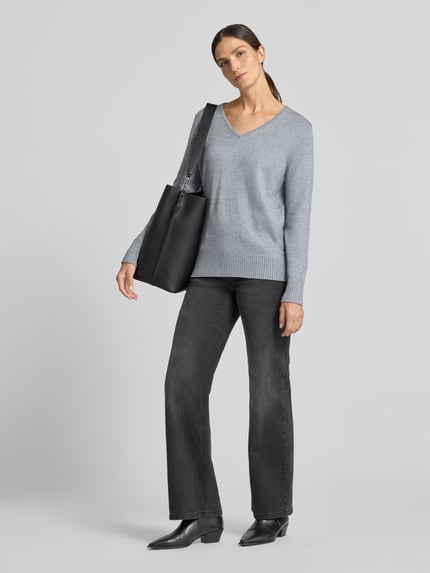 Frauenmodel trägt graues Regular Fit Sweatshirt aus Viskose-Anteil von Christian Berg Woman, V-Ausschnitt, gerippte Abschlüsse, Damen Sweatshirt, Jeans und schwarze Schuhe, Ganzkörperansicht von vorne.