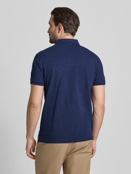 Męski model nosi Koszulkę polo z wyhaftowanym logo Polo Ralph Lauren z bawełny, krój regular fit, kołnierzyk polo, prążkowane zakończenia rękawów, długość tyłu 68 cm przy rozmiarze M, widok całej sylwetki z tyłu.