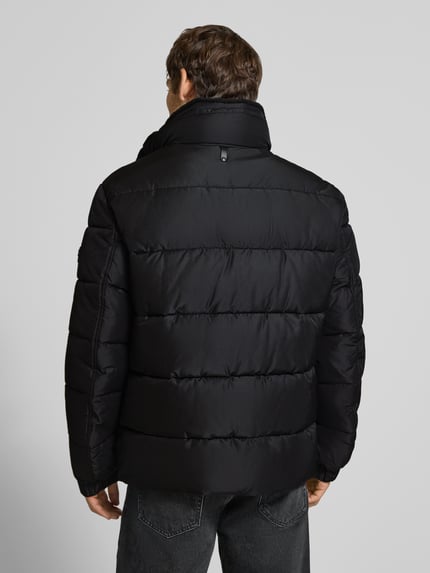 Männermodel trägt schwarze Regular Fit Steppjacke mit Logo-Detail Modell 'Newton' von JOOP!, Herren Bomberjacke, Ganzkörperansicht Rückansicht.