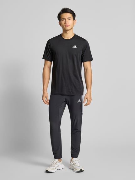 Männermodel trägt T-Shirt mit Logo und Rundhalsausschnitt von adidas Training, Material-Mix mit Baumwoll-Anteil, Regular-Fit, schwarze Farbe, Ganzkörperansicht von vorne