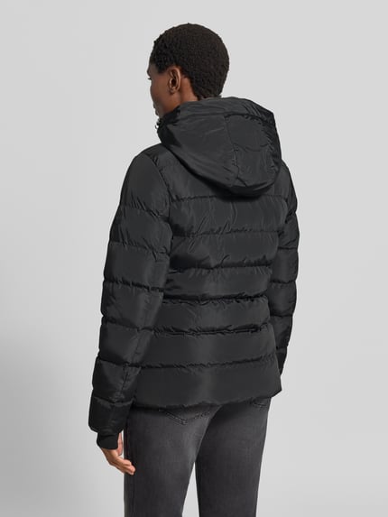 Männermodel trägt czarna kurtka z efektem pikowania Regular fit Modell 'Synria' od Cars Jeans z kapturem, wpuszczane kieszenie, zamek błyskawiczny, Długość tyłu w rozmiarze S: 65 cm, szerokość ramion w rozmiarze S: 42 cm, szerokość klatki piersiowej w rozmiarze S: 50 cm, długość rękawów w rozmiarze S: 70 cm, widok całej sylwetki z tyłu.