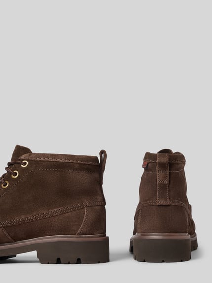 Produktfoto, dunkelbraune Boots aus Leder Modell 'Cleyhill' von Clarks mit profilierter Sohle, abgerundeter Spitze und Schnürung, strukturierte Wildleder-Oberfläche, Absatzhöhe 4 cm, Schafthöhe 11 cm, Schaftweite 10 cm, Herrenmodell vor hellgrauem Hintergrund.