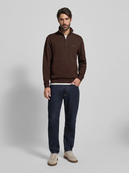 Männermodel trägt Regular Fit Troyer aus Baumwoll-Mix von Tommy Hilfiger, dunkelbraun, mit Label Stitching, Reißverschluss, Rippenbündchen, Ganzkörperansicht von vorne.