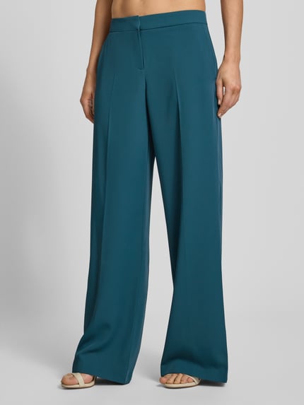 Frauenmodel trägt Hose mit weitem Bein und Paspeltaschen am Gesäß von Jake*s Cocktail in Petrol, Material-Mix mit Stretch, Nahaufnahme Unterkörper.