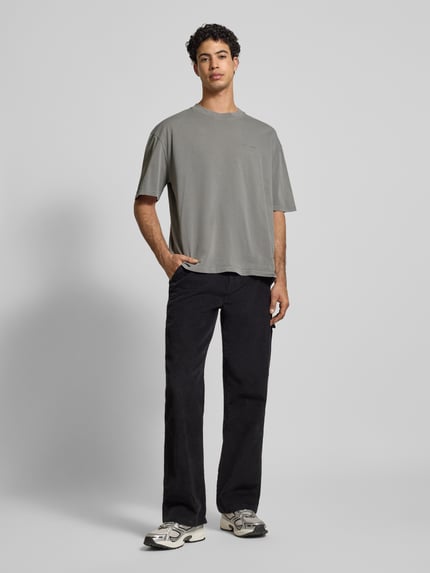 Männermodel trägt Oversized T-Shirt mit Label-Stitching von Pegador aus reiner Baumwolle mit geripptem Rundhalsausschnitt, Ganzkörperansicht von vorne.