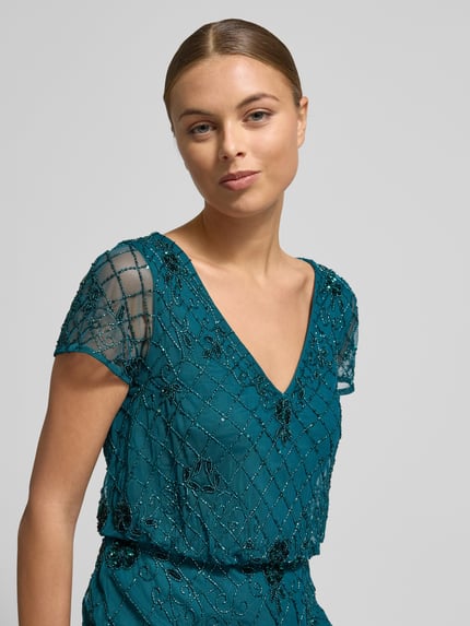 Vrouwenmodel draagt Adrianna Papell avondkleid met V-hals en kralen, getailleerd maxijurk in smaragdgroen, Nahaufnahme bovenlichaam.