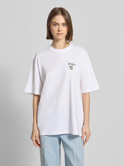 Vrouwenmodel draagt Oversized T-shirt met Statementprint van REVIEW in wit, puur katoen, oversized fit, ronde hals, ruglengte maat S 70 cm, Ganzkörperaanzicht van voren.