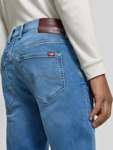 Männermodel trägt Regular Fit Jeans mit Used Waschung von MUSTANG in Medium Wash Denim, 5-Pocket-Design, Ganzkörperansicht Rückansicht.