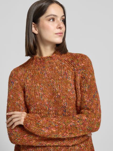 Frauenmodel trägt Strickpullover mit Stehkragen von Rich & Royal, orangefarbener Material-Mix mit Mohairwoll-Anteil, Nahaufnahme Oberkörper.