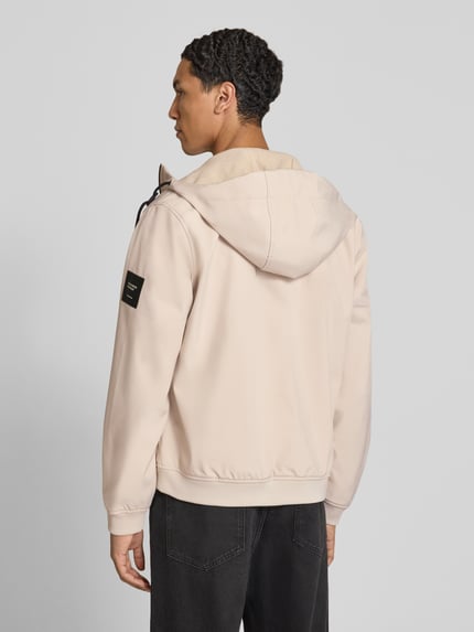 Männermodel trägt Regular Fit Jacke mit Logo-Detail von JACK & JONES in Beige, Kapuze, Softshell, elastische Abschlüsse, Ganzkörperansicht Rückansicht