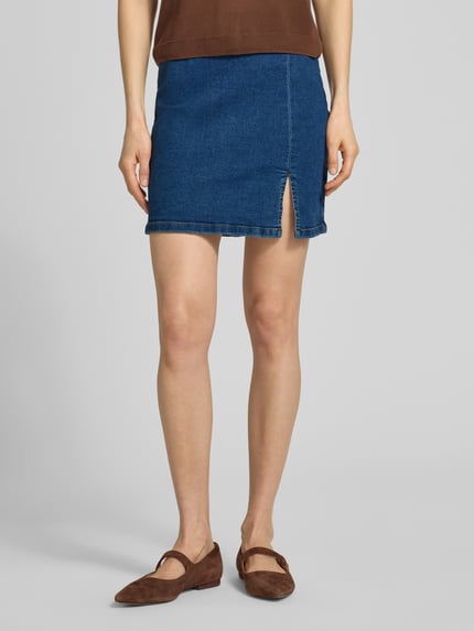 Frauenmodel trägt eng anliegenden Jeansrock aus Baumwoll-Mix Modell 'NELLY' von Vero Moda in Denim-Optik, Mini-Länge, Regular-Fit, Ganzkörperansicht von vorne.