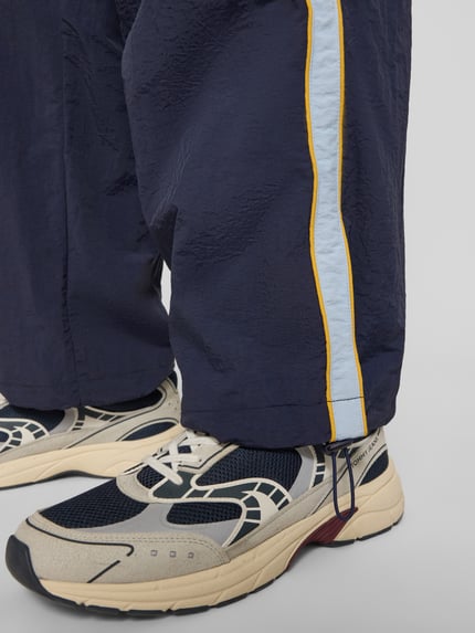 Productfoto, Trackpants met Label-Stitching model 'SLIPSTREAM' van PROHIBITED, relaxed fit, elastische tailleband, navyblauw met lichtblauwe en gele streep, binnenbeenlengte maat M 74 cm, textuur met kreukeleffect.