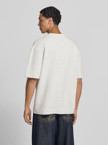 Männermodel trägt Oversized T-Shirt mit Strukturmuster und Label-Stitching von Pegador aus reiner Baumwolle, Rückenansicht Ganzkörperansicht.