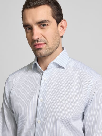 Männermodel trägt Regular Fit Business-Hemd mit Kentkragen von OLYMP aus reiner Baumwolle, feines Streifenmuster, Nahaufnahme Oberkörper.