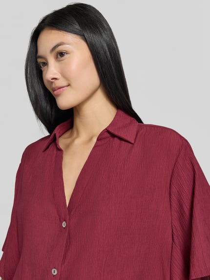 Kobiece model prezentuje Boxy Fit Kurzarmbluse aus Viskose-Mix od s.Oliver RED LABEL w kolorze bordowym, faktura lekko marszczona, zbliżenie na górną część ciała