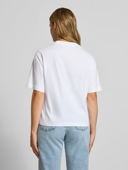 Vrouwenmodel draagt wit regular fit t-shirt van puur katoen, Model 'CHESTER' van Carhartt Work In Progress, halflange mouwen, opstaande kraag, ruglengte bij maat S 56 cm, volledig zichtbaar in achteraanzicht.