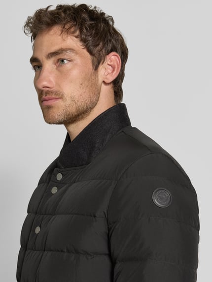 Männermodel trägt Regular Fit Jacke in Stepp-Optik Modell 'Joen' von Tiger of Sweden, schwarze Farbe, Nahaufnahme Oberkörper.