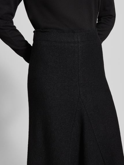 Frauenmodel trägt Midirock aus Viskose-Woll-Mix von Christian Berg Woman in Schwarz, A-Linie mit Teilungsnähten, Nahaufnahme Oberkörper.