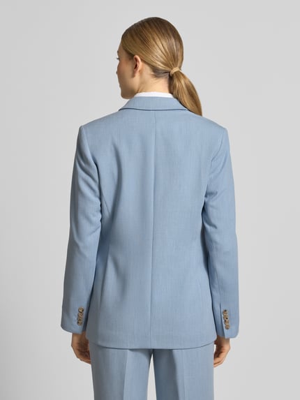 Modelka kobieca ma na sobie Regular Fit Longblazer mit Reverskragen Model 'RITA' od Selected Femme, efekt: jednolity kolor, krój regular fit, kołnierz z połami, zapięcie na 2 guziki, długi rękaw z nachodzącymi na siebie guzikami, kieszenie z patką; widok całej sylwetki z tyłu.