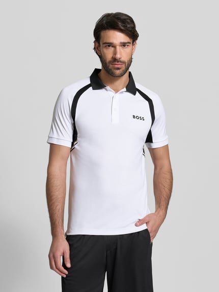 Männermodel trägt Slim Fit Poloshirt mit kurzer Knopfleiste Modell 'PL_TOC SPIN CB' von BOSS Green in uni Jersey, Label Print, Polokragen, ganzkörperansicht von vorne