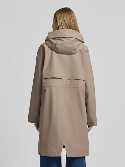 Frauenmodel trägt Parka mit Pattentaschen Modell 'ELINA' von Didriksons in Beige, Relaxed Fit, glatte Textur, Ganzkörperansicht Rückansicht.