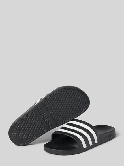 Produktfoto, Badeschuhe mit Kontraststreifen Modell 'ADILETTE AQUA' von adidas, schwarz mit weißem Streifenmuster, strukturierte Sohle, flacher Absatz, Allover-Muster, runde Schuhspitze, Schlupfform