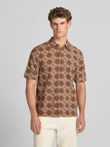 Männermodel trägt Regular Fit Freizeithemd aus reiner Baumwolle Modell 'JOHNSON' von Only & Sons, Optik:Allover-Muster, Kentkragen, einreihige Knopfleiste, Kurzarm, Rumpfabschluss mit Seitenschlitzen, braun-weißes Muster, Ganzkörperansicht von vorne.