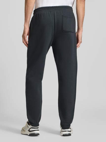 Männermodel trägt Regular Fit Sweatpants aus Mieszanka bawełny z wyhaftowane logo od New Balance, krój regular fit, pas z tunelem, długość wewnętrzna nogawki w rozmiarze M: 79 cm, Ganzkörperansicht Rückansicht.