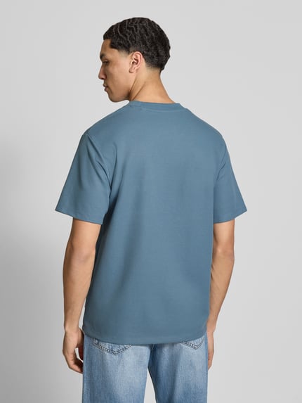 Männermodel trägt T-Shirt mit Rundhalsausschnitt Modell 'AUSTIN' von Jack & Jones in Blau, Elastischer-Material-Mix, Gerader-Schnitt, Rückenlänge 68 cm, Ganzkörperansicht Rückansicht.