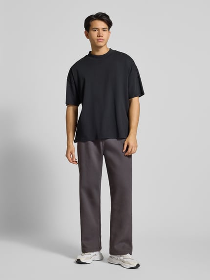 Männermodel trägt Sweatpants mit elastischem Bund von adidas Originals, Baumwoll-Mix, Lockerer-Schnitt, Label-Stitching, Farbe grau, französische Eingrifftaschen, Innenbeinlänge bei Größe M 77 cm, Ganzkörperansicht von vorne.
