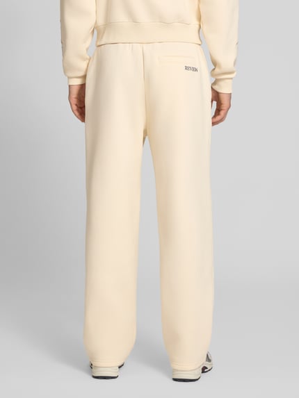 Männermodel trägt Straight Fit Sweatpants mit floraler Stickerei von REVIEW in Beige, Baumwoll-Mix, elastischer Bund, Ganzkörperansicht Rückansicht.