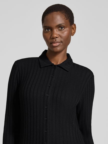 Frauenmodel trägt Cropped Langarmshirt mit durchgehender Knopfleiste Modell 'Sitami' von OPUS in schwarzer Rippstrick-Struktur, Nahaufnahme Oberkörper.