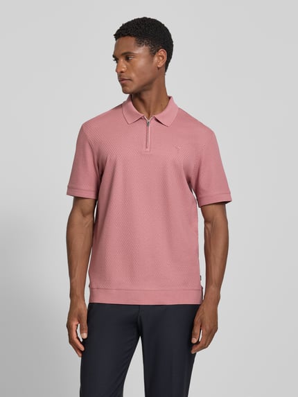 Männermodel trägt Regular Fit Poloshirt mit Strukturmuster Modell 'Tibaris' von JOOP! COLLECTION in Rosa mit Label-Stitching, Polokragen, Reißverschluss, Rückenlänge 70 cm bei Größe M, Ganzkörperansicht von vorne.