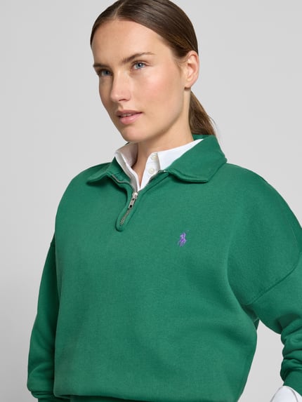 Frauenmodel trägt Regular Fit Pullover aus Baumwoll-Mix von Polo Ralph Lauren in Grün mit lilafarbenem Logo, Nahaufnahme Oberkörper. Damen Pullover von Polo Ralph Lauren