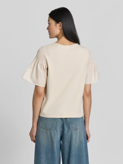Frauenmodel trägt Regular Fit T-Shirt mit Smok-Detail von Comma aus reiner Baumwolle, ausgestellte Ärmel, kurzärmelig, cremefarben, Ganzkörperansicht Rückansicht.