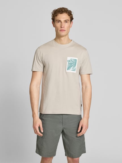 Męski model nosi Regular Fit T-Shirt aus reiner Baumwolle Modell 'TE_BOARD' von BOSS Orange, kremowy, krój regular fit, unikolor, nadruk foto, detal z logo, okrągły dekolt, krótkie rękawy, jersey, bawełna; widok całej sylwetki z przodu.