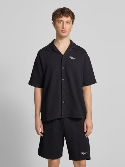 Männermodel trägt zwart heren vrijetijdsoverhemd Regular Fit model 'Jovren' van Pegador in elastische materiaalmix met katoen, halflange mouwen, reverskraag, knoopsluiting en labelstitching, ruglengte maat M 72 cm, schouderbreedte 45 cm, mouwlengte 33 cm, gestructureerde textuur, voorkant, Ganzkörperansicht von vorne.