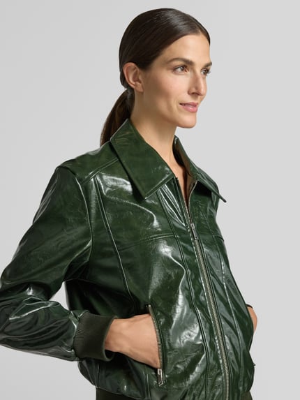 Frauenmodel trägt Jacke mit Reißverschlusstaschen Modell 'Janny' von FREE/QUENT in glänzendem Dunkelgrün, Kentkragen, seitliche Taschen, Nahaufnahme Oberkörper.