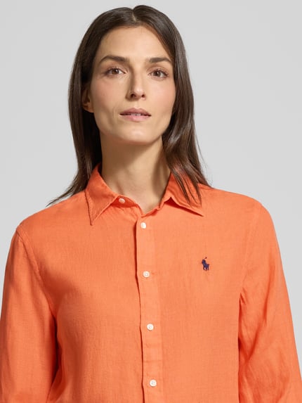 Kobieta nosi Hemdbluse mit Knopfleiste od Polo Ralph Lauren z czystego lnu, luźny krój, pomarańczowy kolor, zbliżenie na górną część ciała.