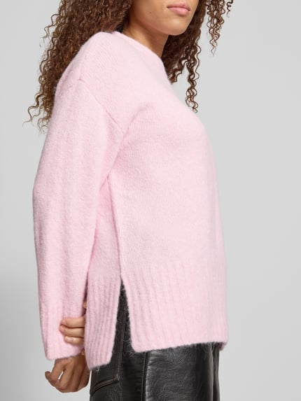 Modelka nosi sweter z okrągłym dekoltem PIECES, krój regular fit, jednokolorowy, długi, prążkowane wykończenia, widok z boku.