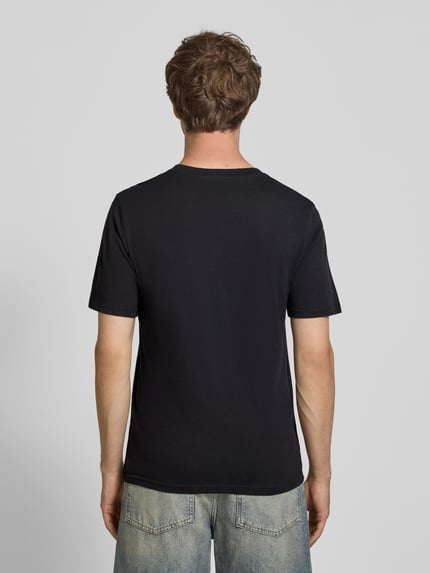 Männermodel trägt Regular Fit T-Shirt mit Logo-Print Modell 'Buster' von JACK & JONES aus reiner Baumwolle, Ganzkörperansicht Rückansicht.