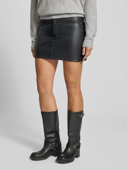 Frauenmodel trägt Minirock in Leder-Optik mit Eingrifftaschen von REVIEW, schwarz, A-Linie, sichtbare Nähte, Nahaufnahme Unterkörper.