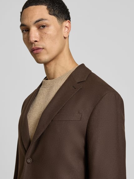 Männermodel trägt Regular Fit Sakko aus reiner Schurwolle von Officine Générale in Braun mit Reverskragen und Knopfverschluss, Nahaufnahme Oberkörper. Rückenlänge 73 cm, Schulterbreite 46 cm, Ärmellänge 62 cm.